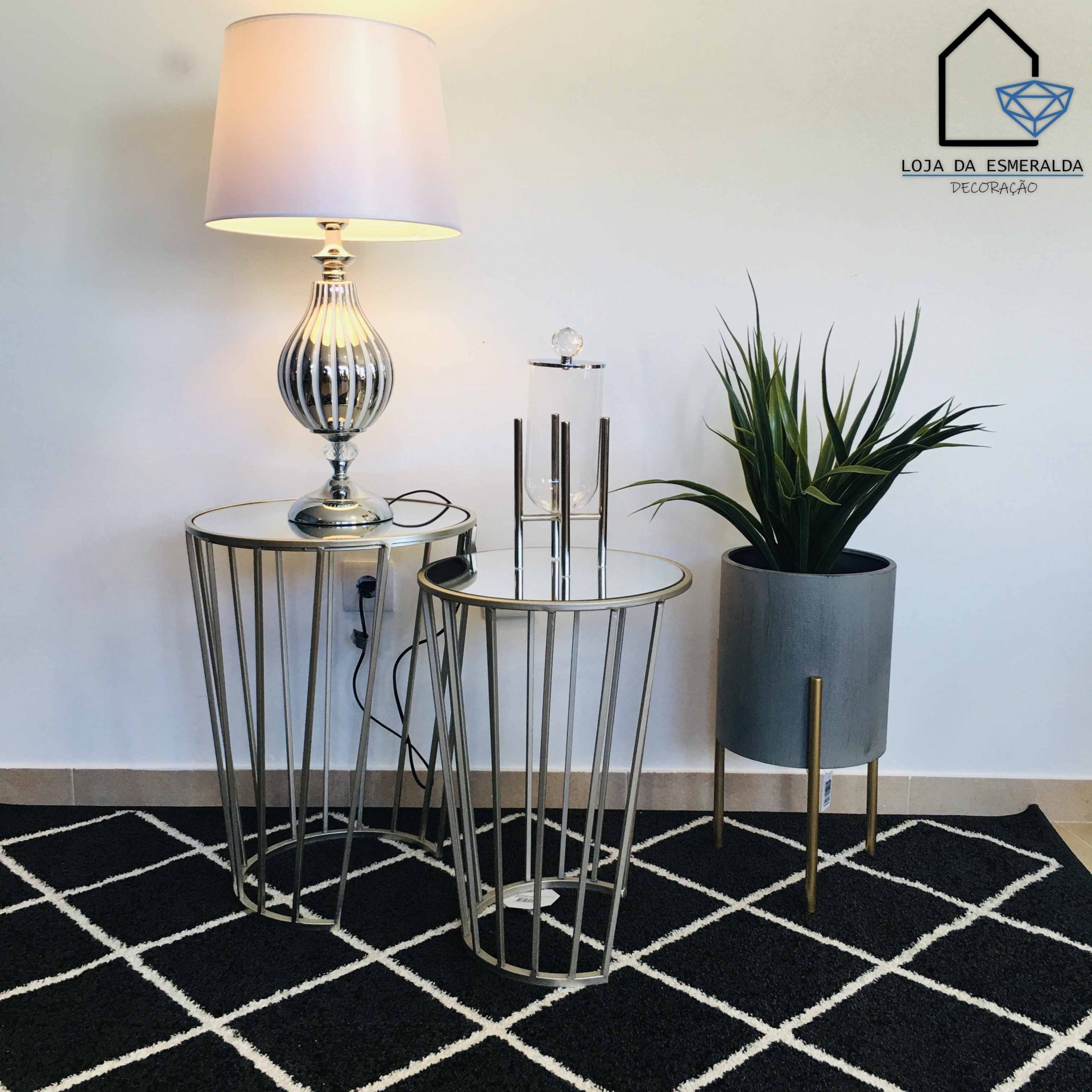 Conjunto de mesas metálicas com tampo espelhado, lâmpada com base metálica e planta em vaso cinzento