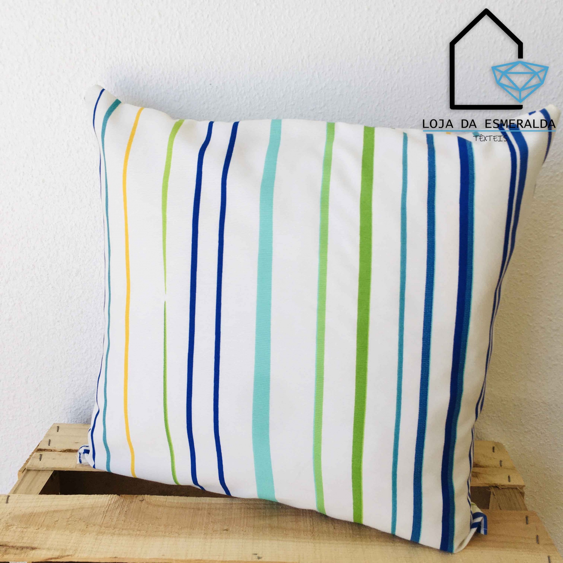 Almofada com riscas coloridas sobre caixa de madeira