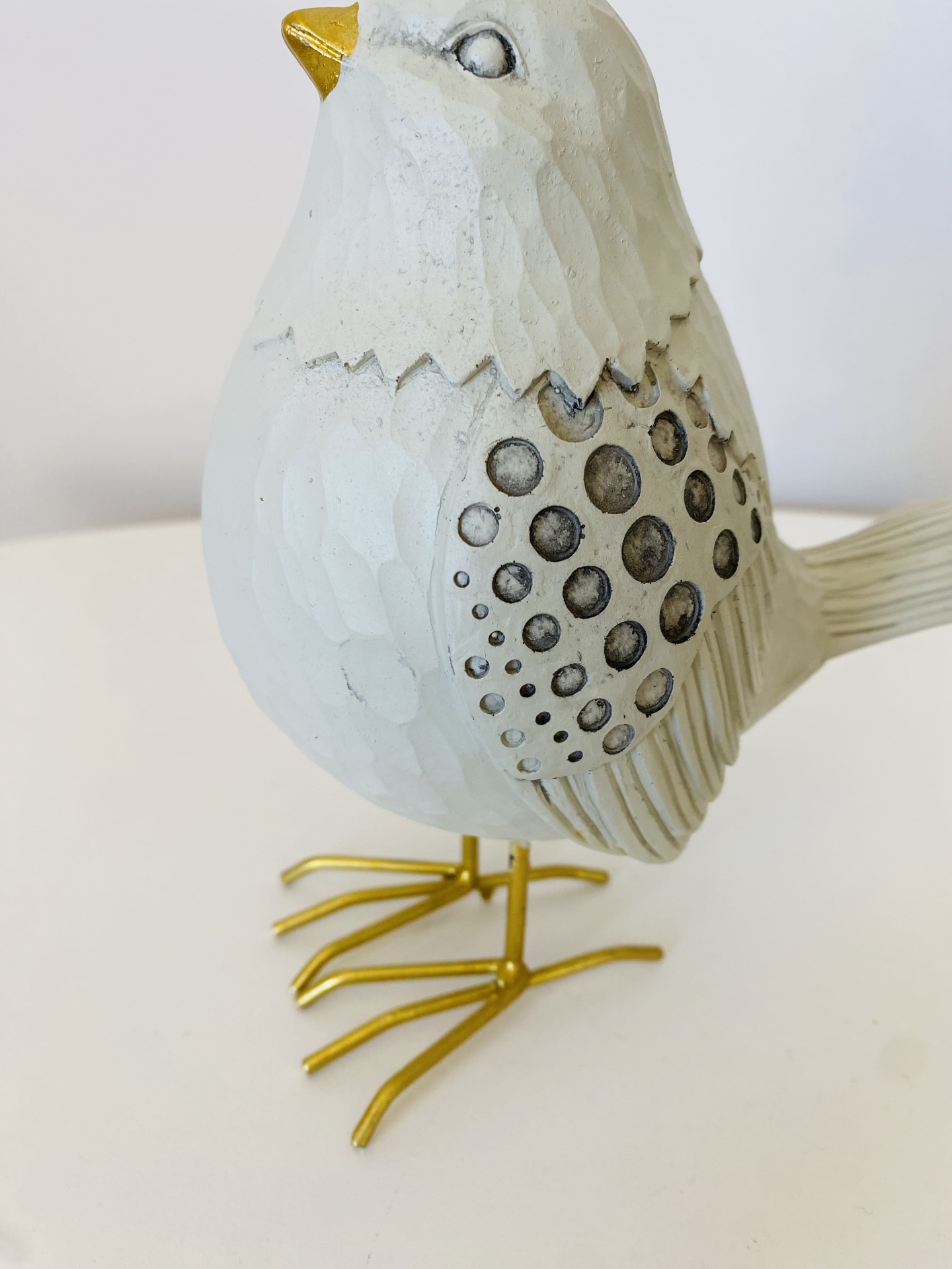 Escultura decorativa de pássaro branco com detalhes dourados e cinzentos