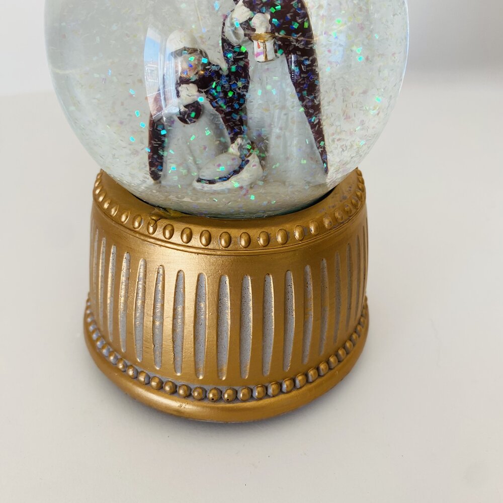 Globo de neve decorativo com duas figuras femininas e base dourada