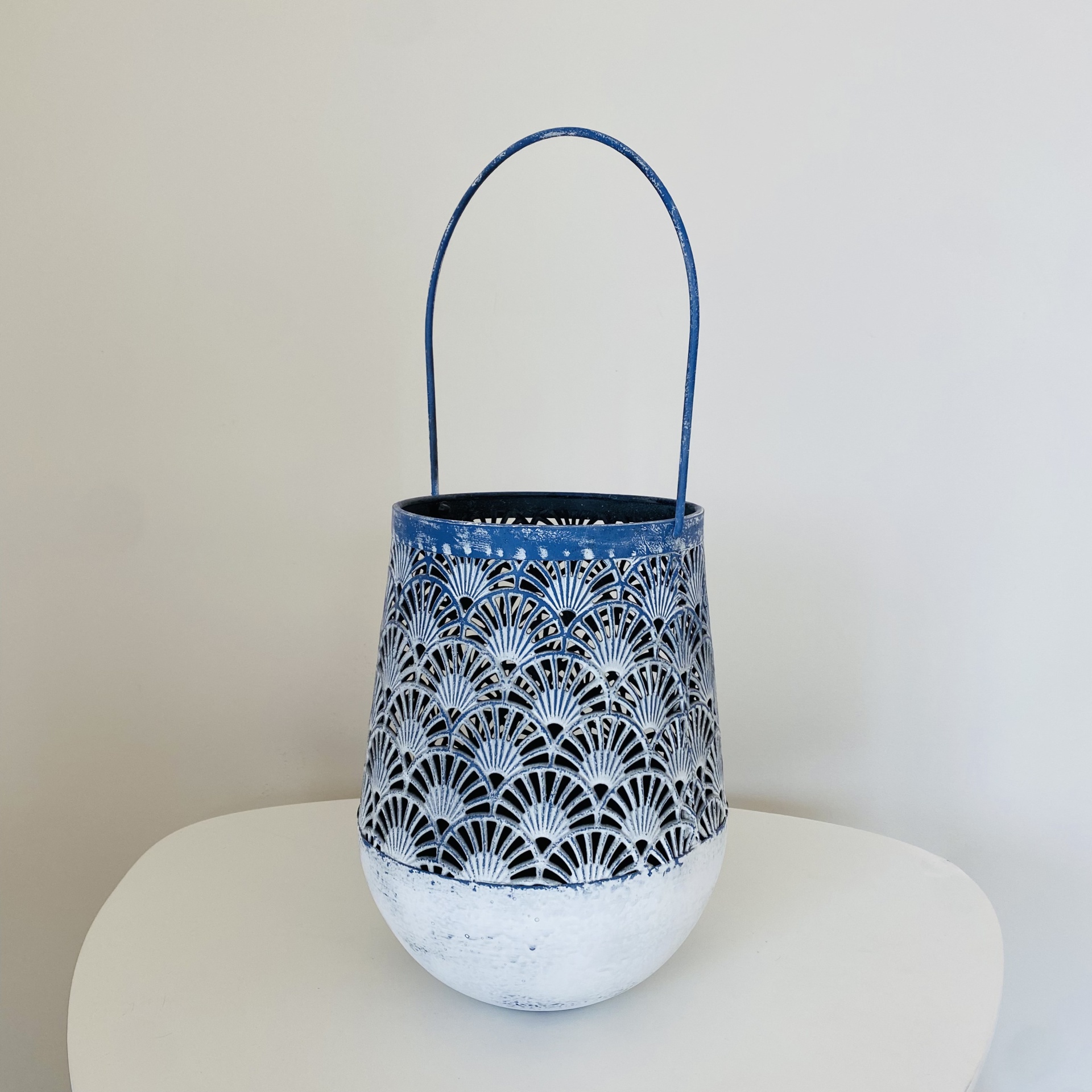 Lanterna em metal azul e branco com padrão recortado e alça
