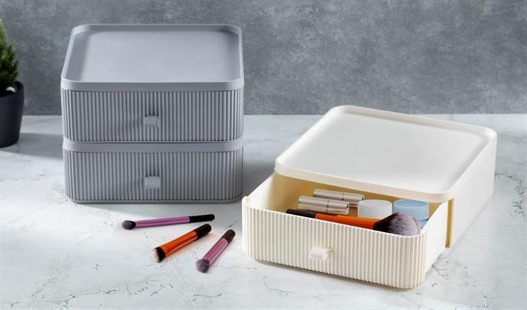 Caixas organizadoras plásticas cinza e creme com pincéis e recipientes de maquilhagem