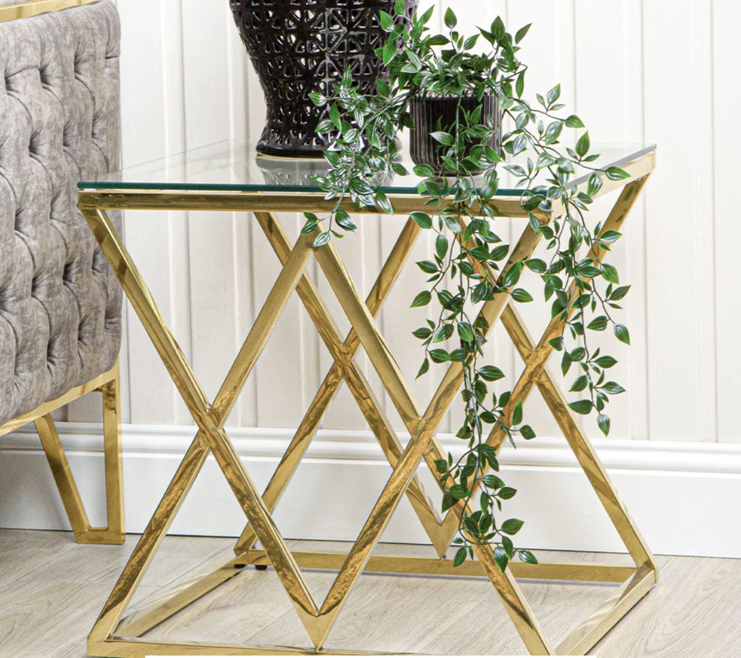 Mesa de apoio dourada com tampo de vidro e planta verde