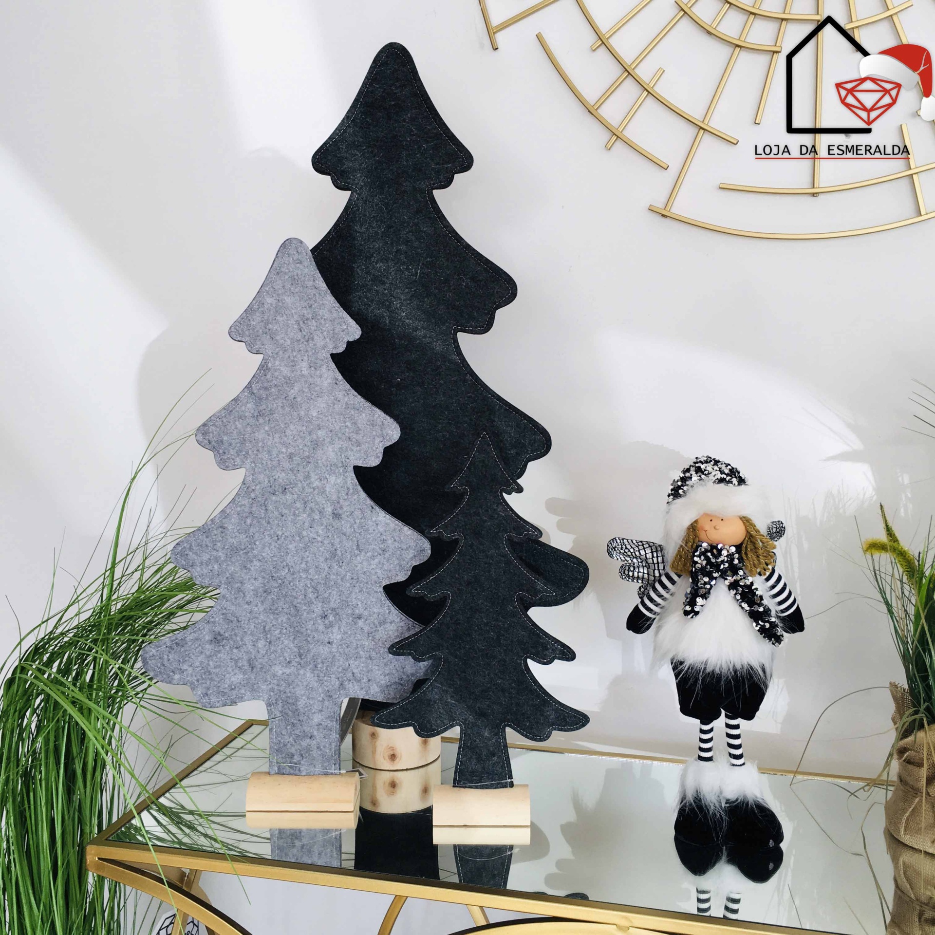 Três árvores decorativas de feltro e uma figura preta e branca em cenário minimalista