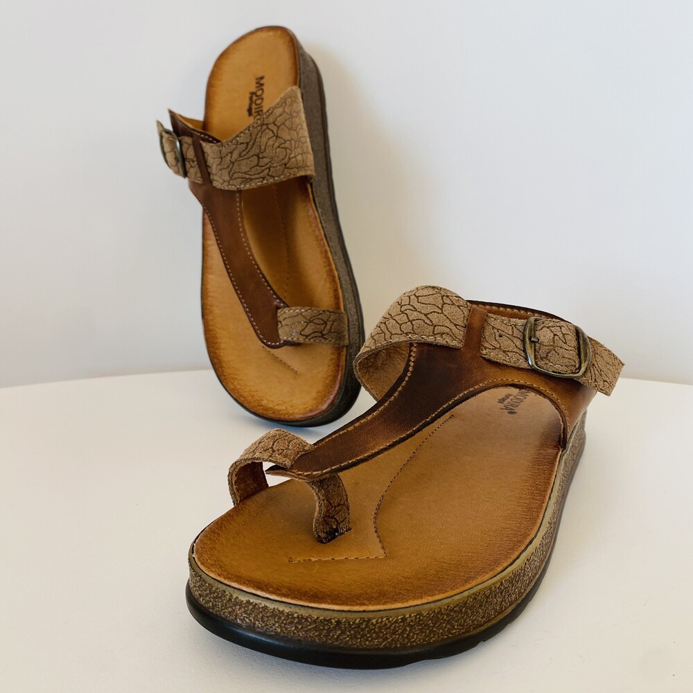 Sandálias de dedo bege e castanho com sola castanha sobre superfície branca