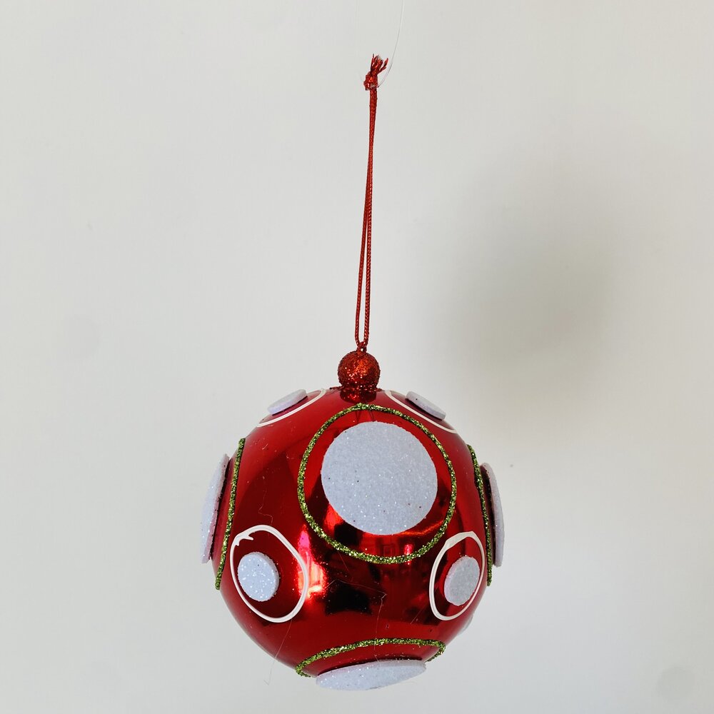 Bola de Natal vermelha com círculos brancos e detalhes dourados pendurada