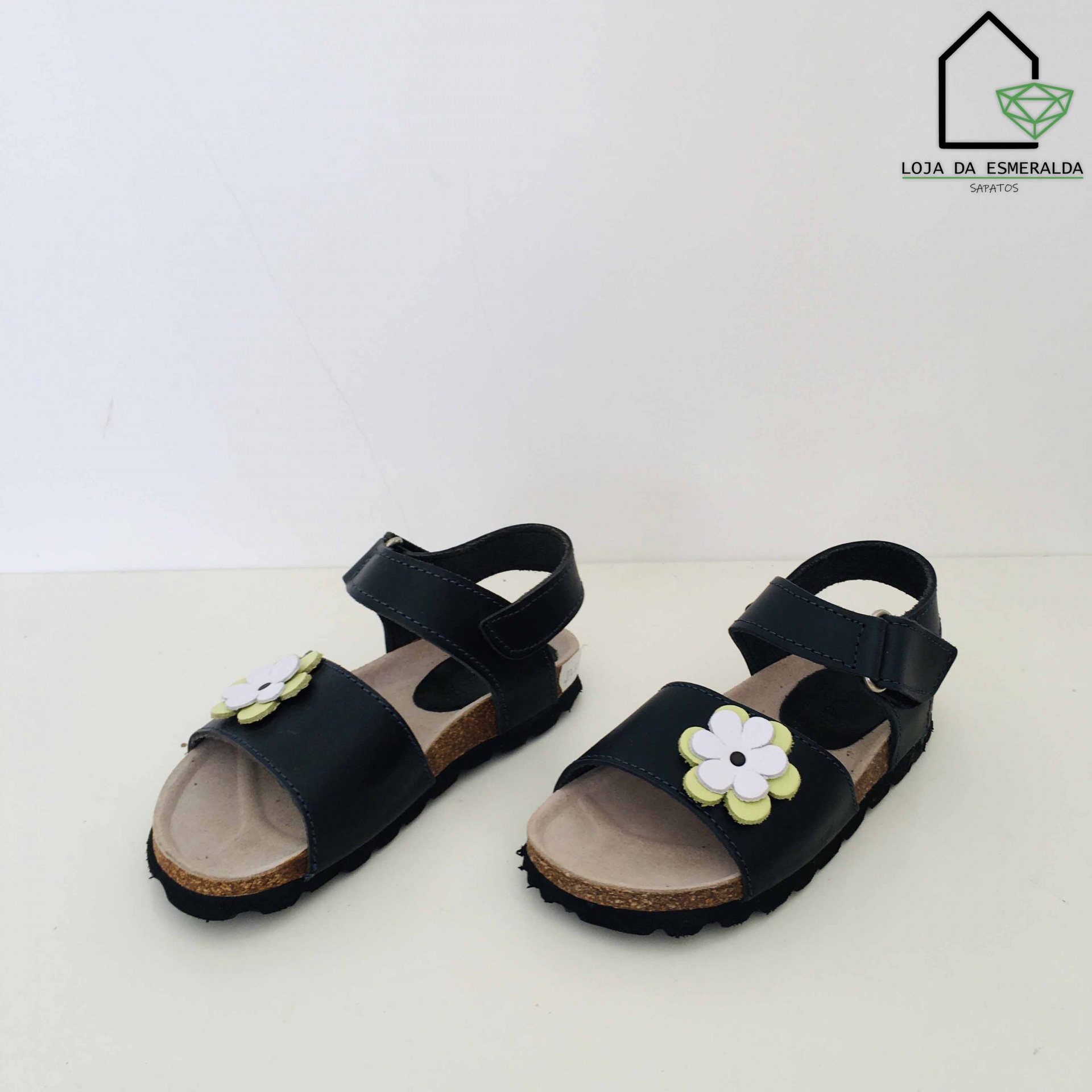 Sandálias infantis pretas com flor branca e amarela em fundo branco