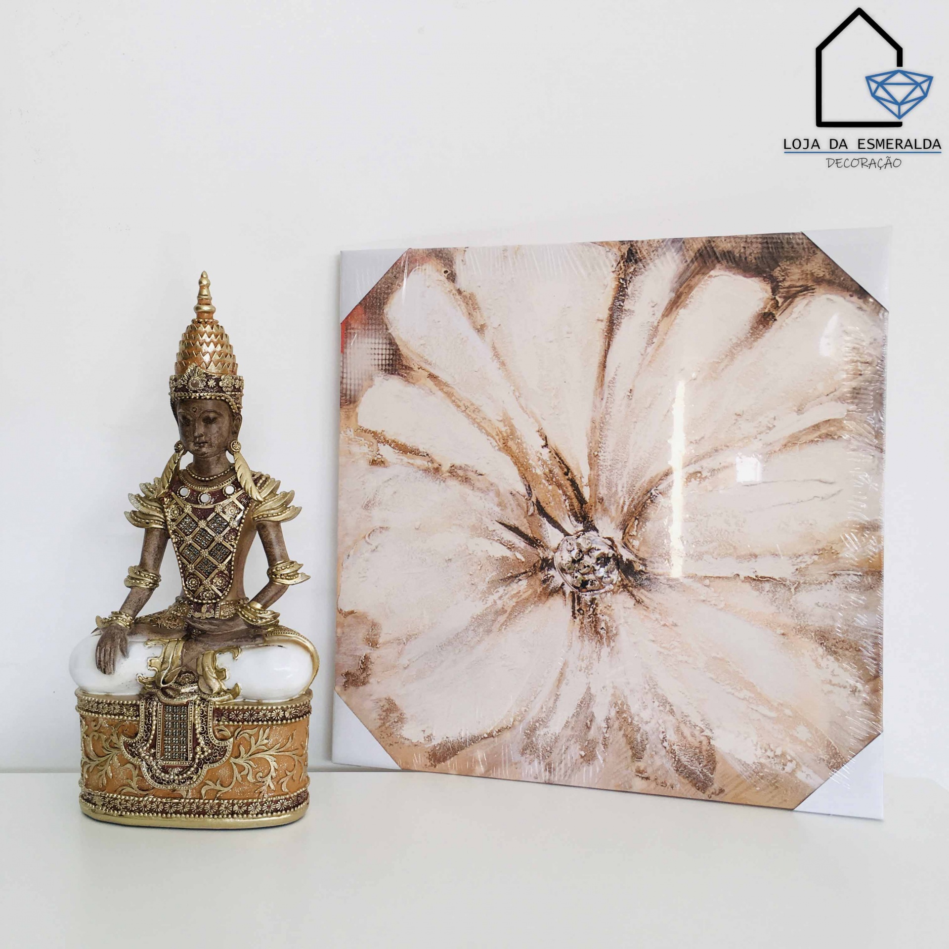 Escultura dourada oriental e pintura abstrata bege sobre mesa branca