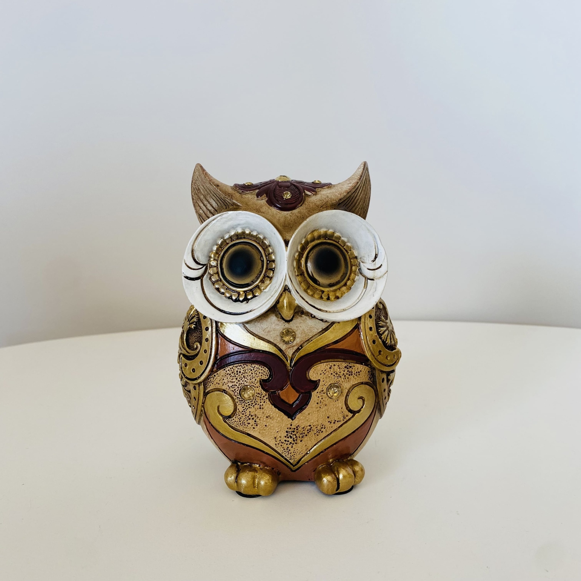 Estatueta de coruja decorativa em cerâmica com olhos grandes e detalhes em dourado e castanho