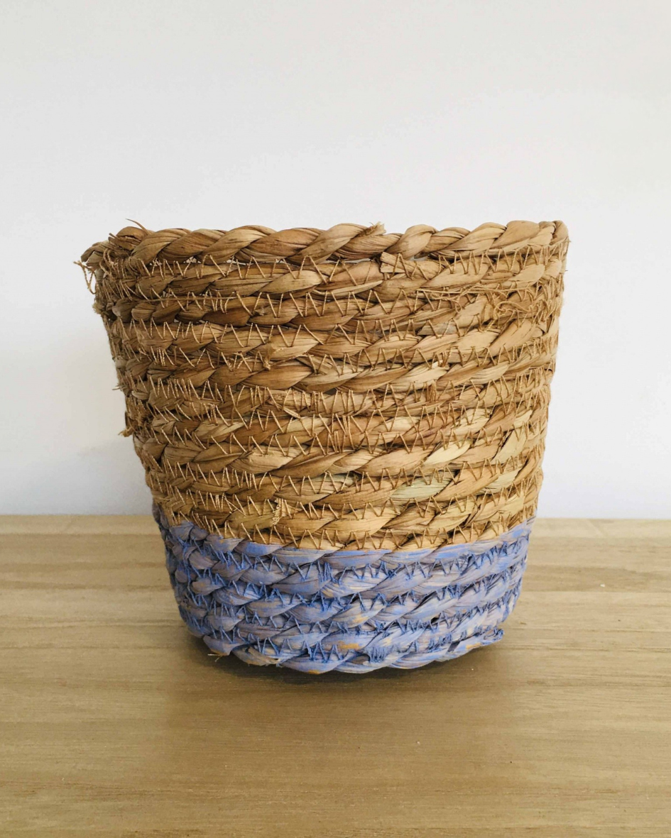 Cesto trançado de palha natural com base azul numa mesa de madeira