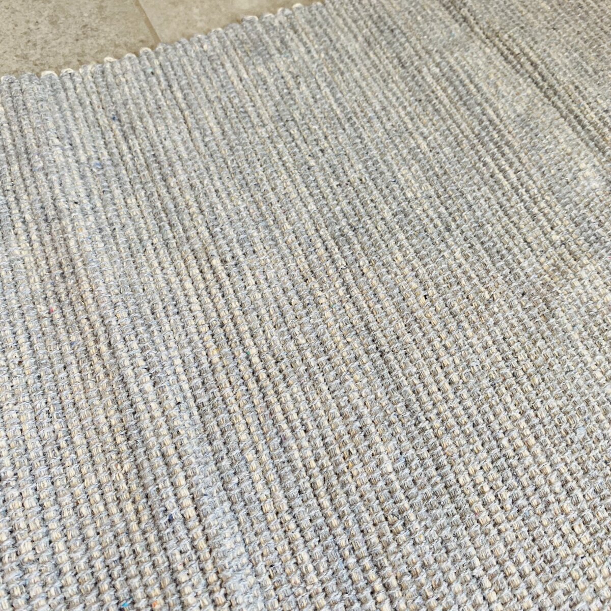 Tapete tecido bege e cinza claro sobre piso de cerâmica