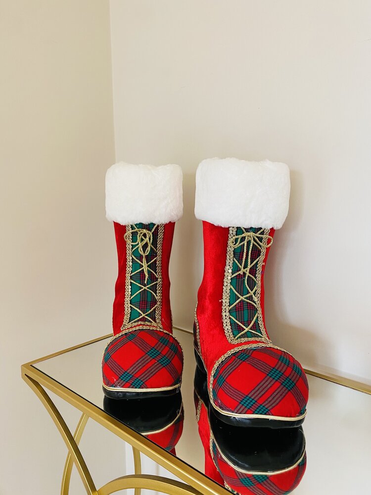 Botas decorativas vermelhas com padrão xadrez, detalhes em branco peludo e dourado, sobre mesa de vidro dourada