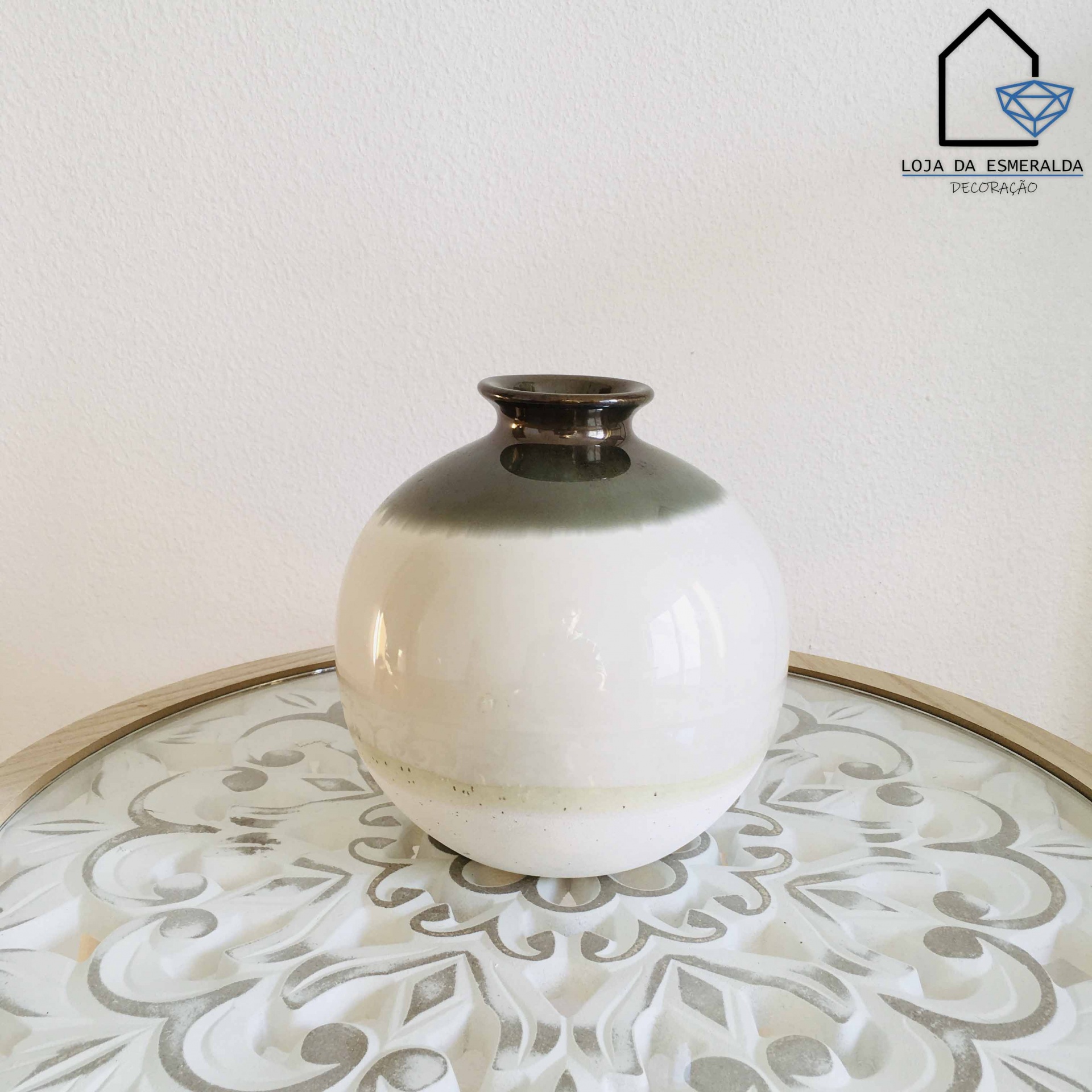Vaso cerâmico redondo bicolor sobre mesa decorativa branca com padrão floral