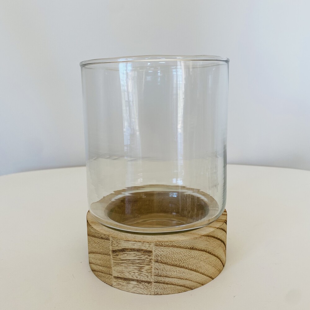 Copo de vidro transparente com base de madeira clara em superfície branca