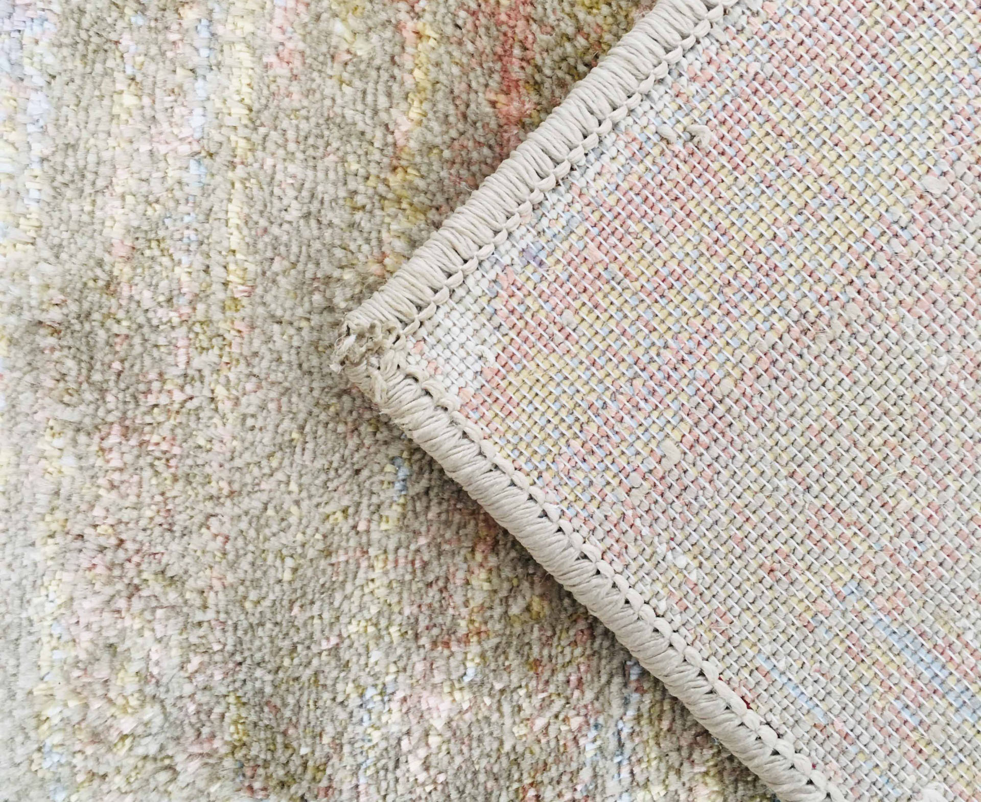 tapete pastel com acabamento costurado dobra sobre tapete neutro