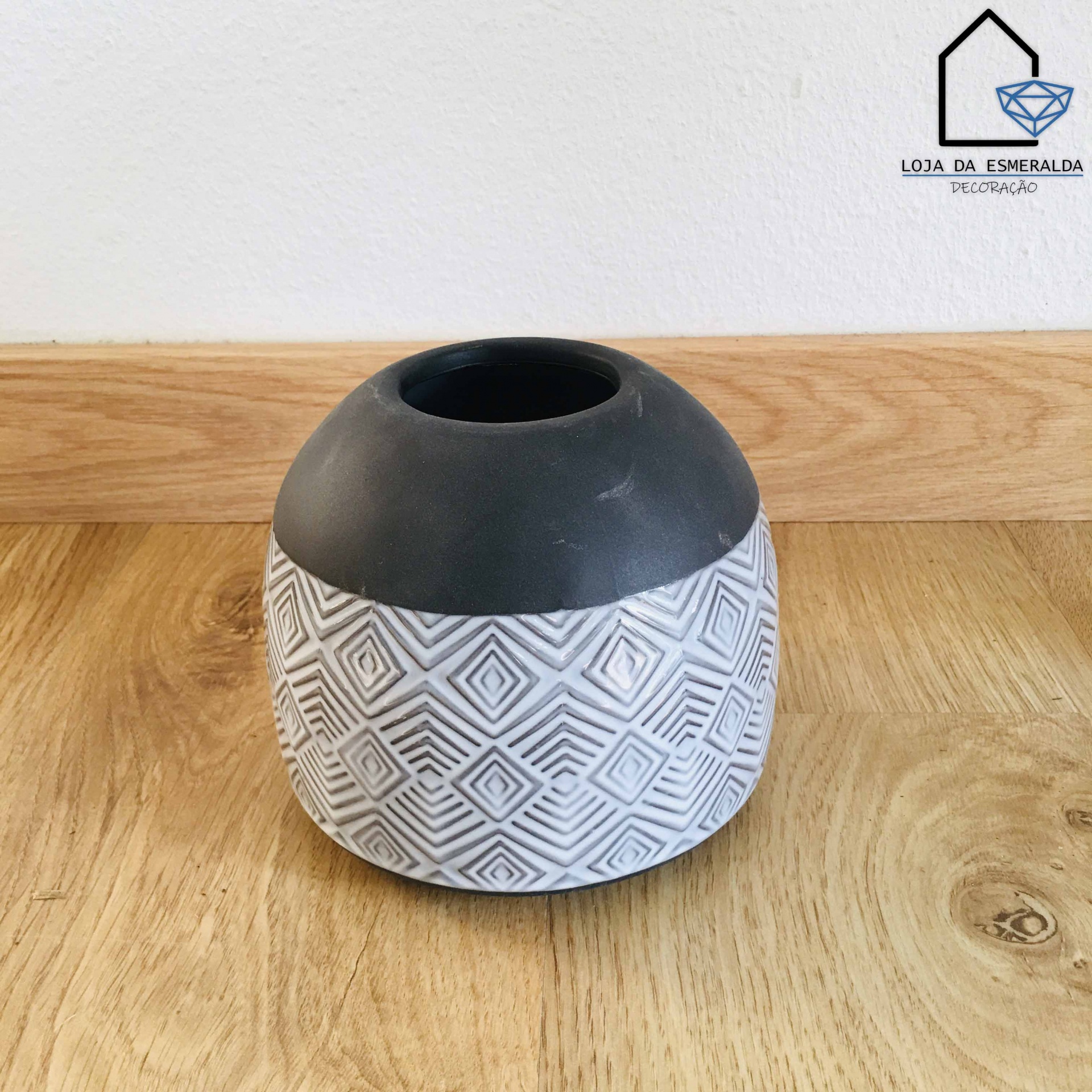 Vaso decorativo preto e branco com padrão geométrico sobre superfície de madeira