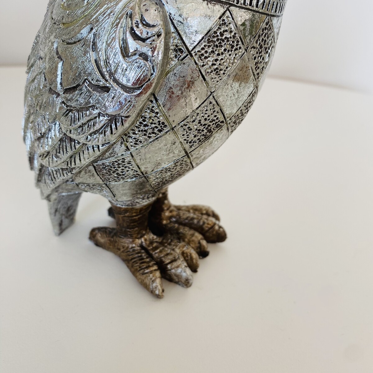 Escultura de coruja metálica prateada e dourada com textura detalhada