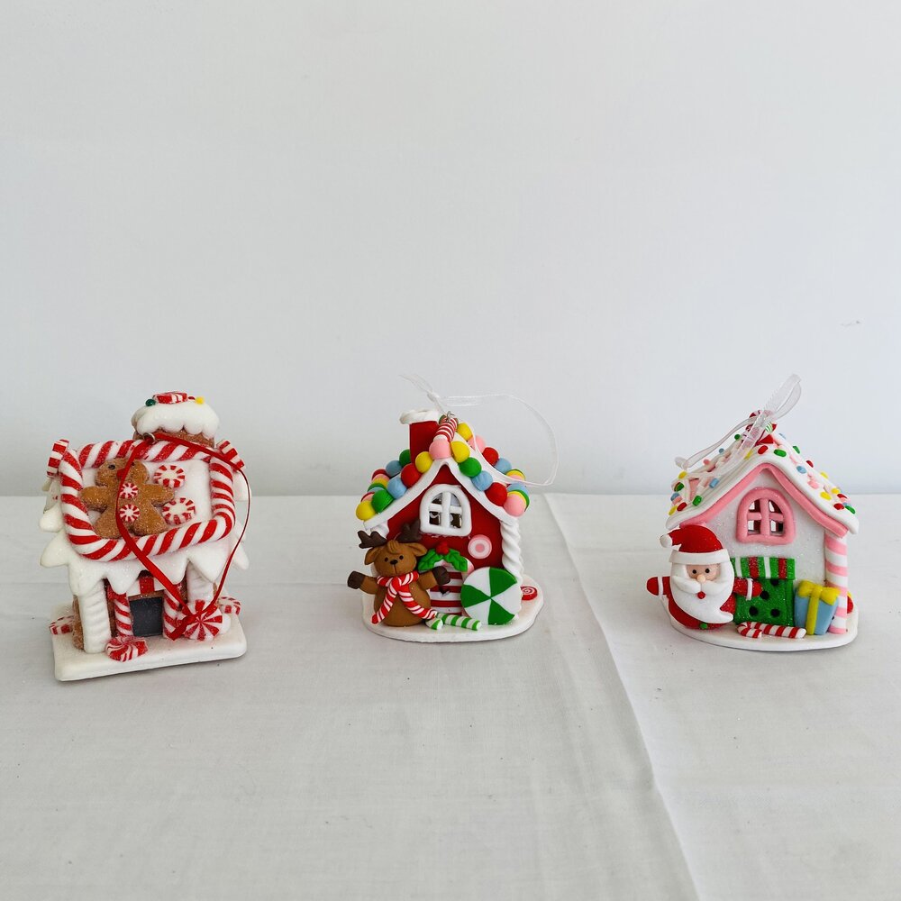 Três casas decorativas de Natal coloridas em miniatura sobre superfícies brancas