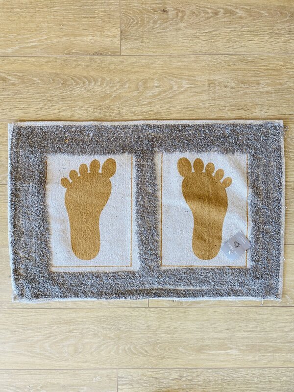 Tapete para casa de banho com pés amarelos sobre fundo branco e moldura cinza