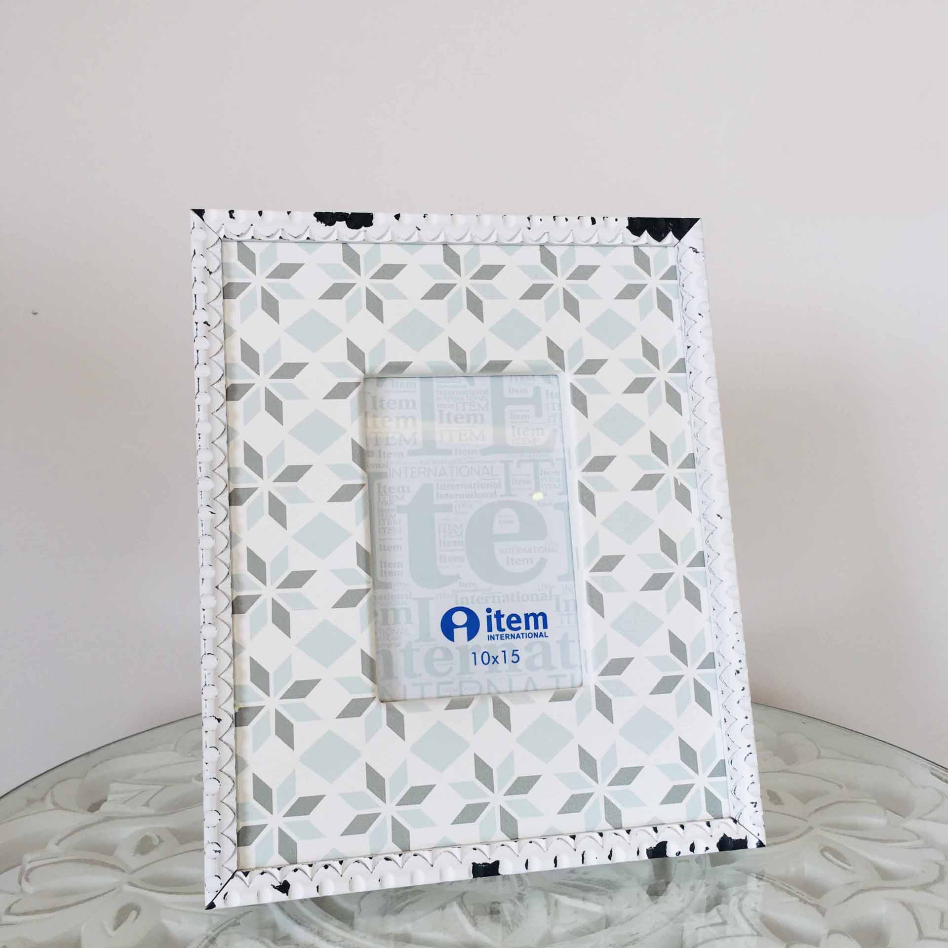 Moldura fotográfica geométrica cinza e branca sobre mesa de vidro