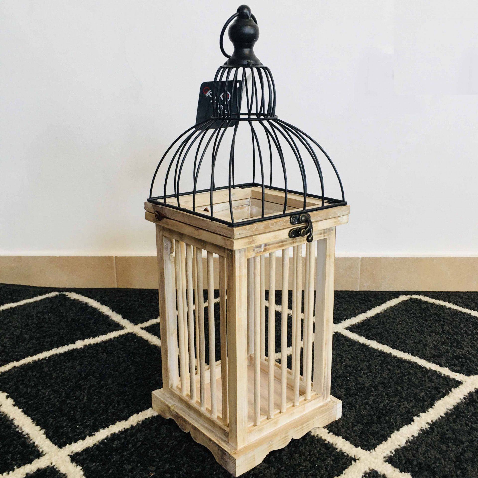 Lanterna decorativa de madeira clara e metal preto com padrão de tapete preto e branco