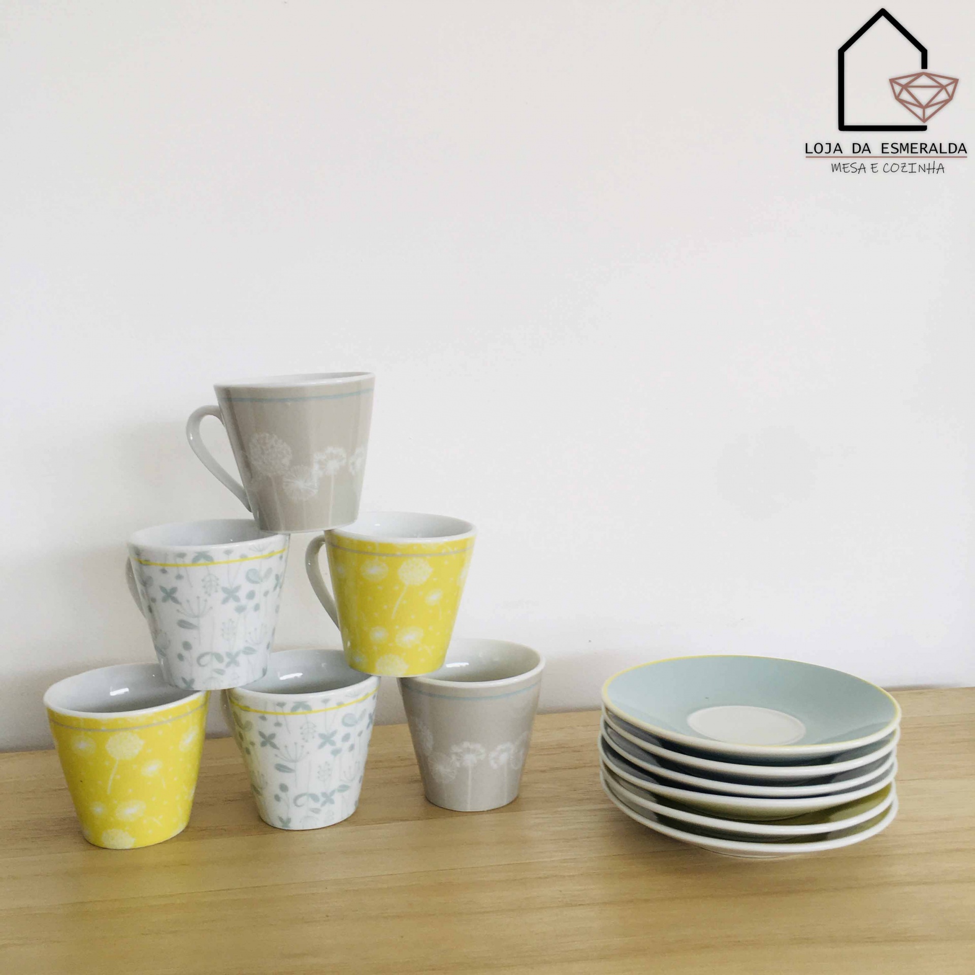 Conjunto de chávenas coloridas e pratos empilhados sobre mesa de madeira