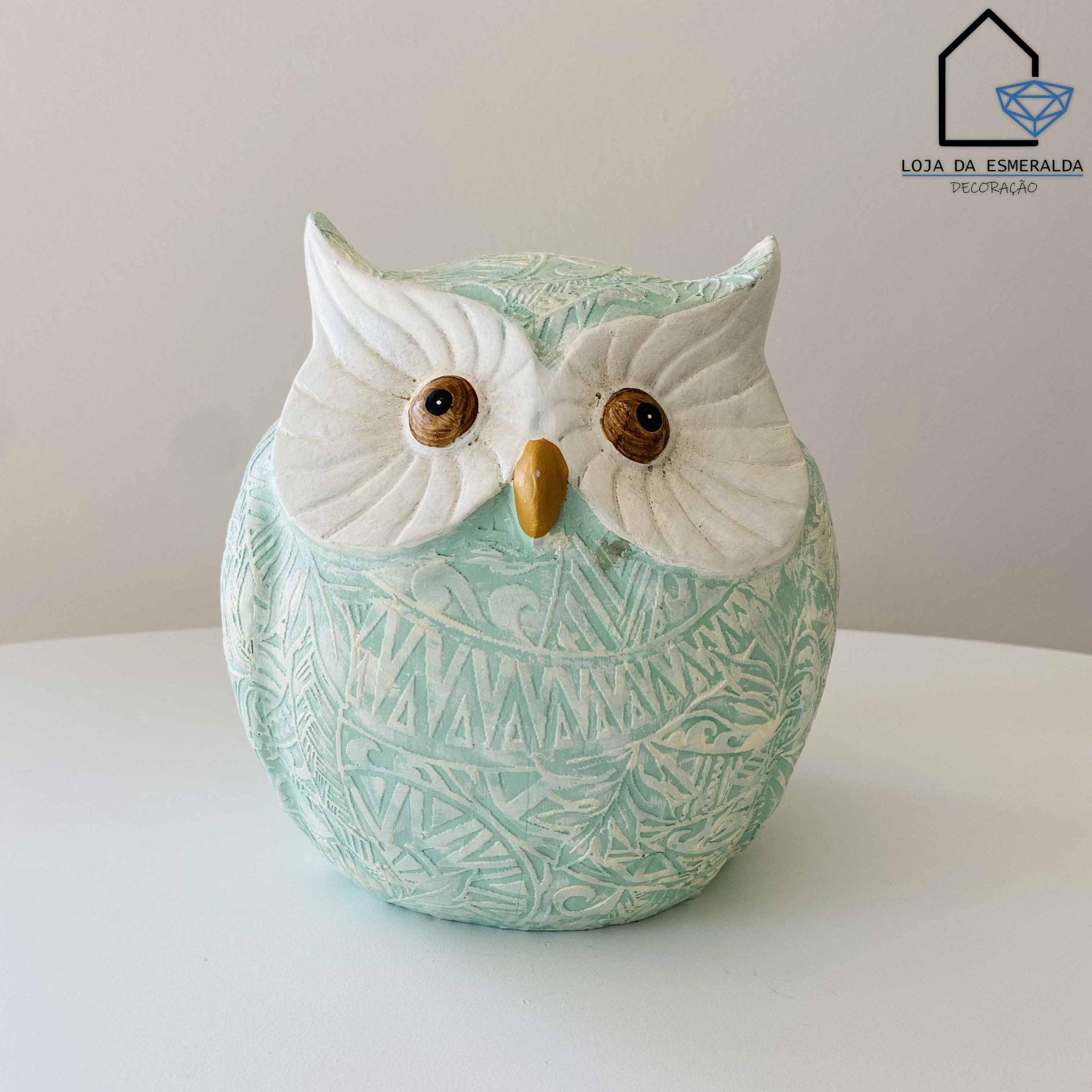 Estatueta coruja cerâmica verde água com olhos brancos e detalhes castanhos sobre superfície branca
