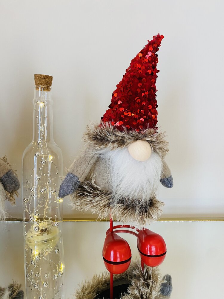 Boneco decorativo de Natal com gorro vermelho e barba branca ao lado de garrafa de vidro com luzes