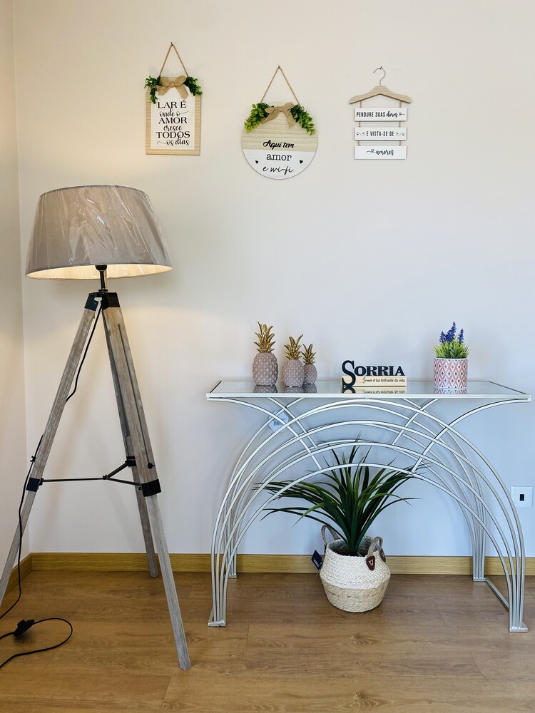 candeeiro de pé e mesa metálica branca com decoração e placas de parede