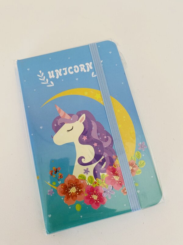 Caderno azul com ilustração de unicórnio, flores, lua e banda elástica