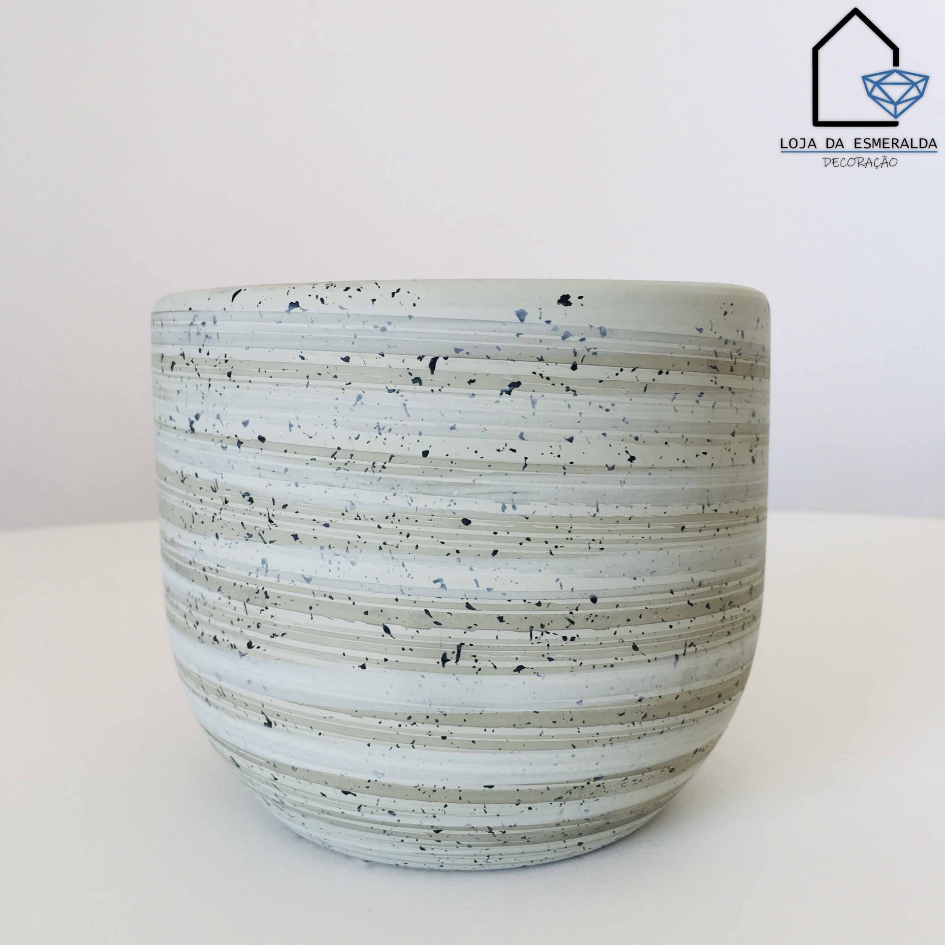 Vaso cerâmico listrado branco e cinza com manchas pretas em fundo branco.
