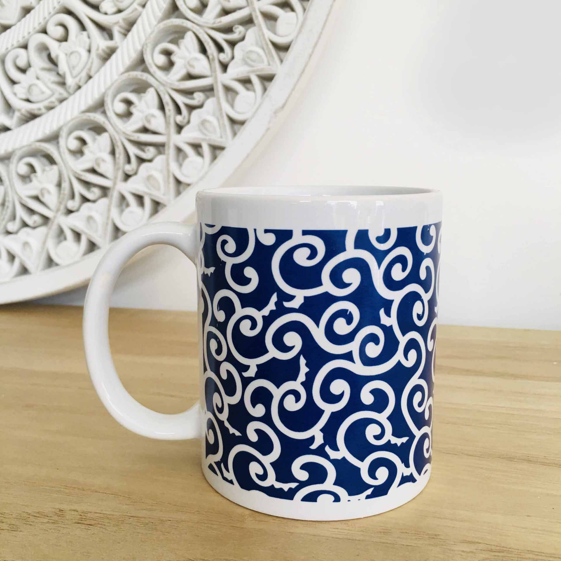 Caneca branca com padrão azul de arabescos brancos