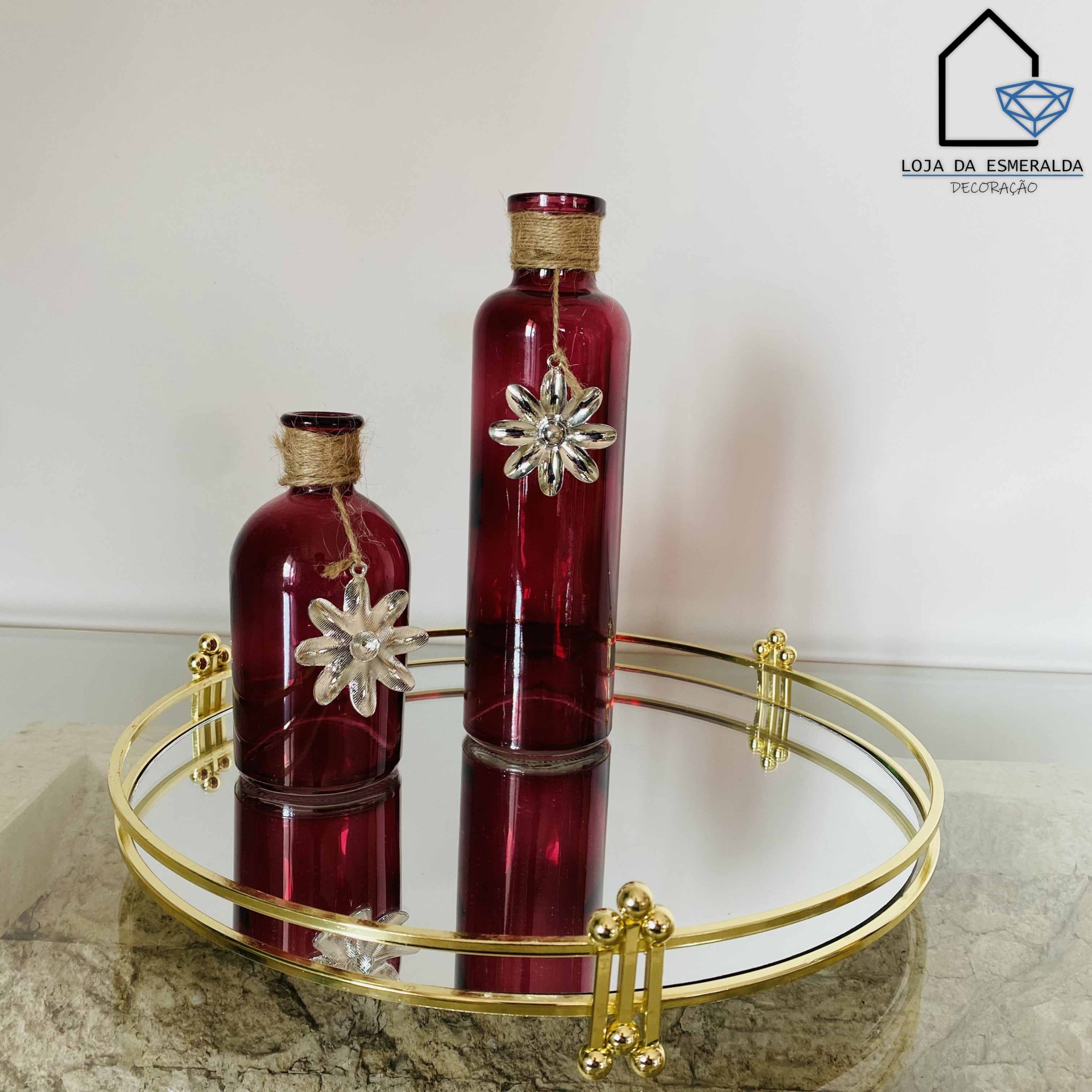 Duas garrafas vermelhas decorativas sobre uma bandeja espelhada dourada