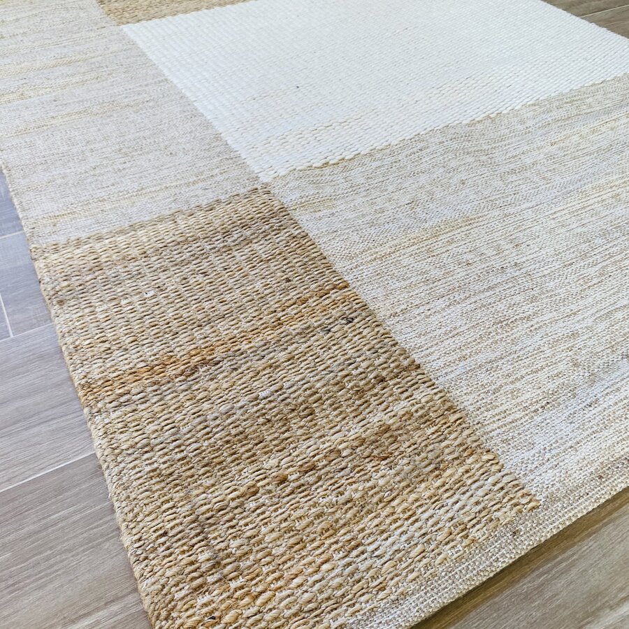 Tapete retangular com padrão quadriculado em tons neutros sobre chão de madeira clara