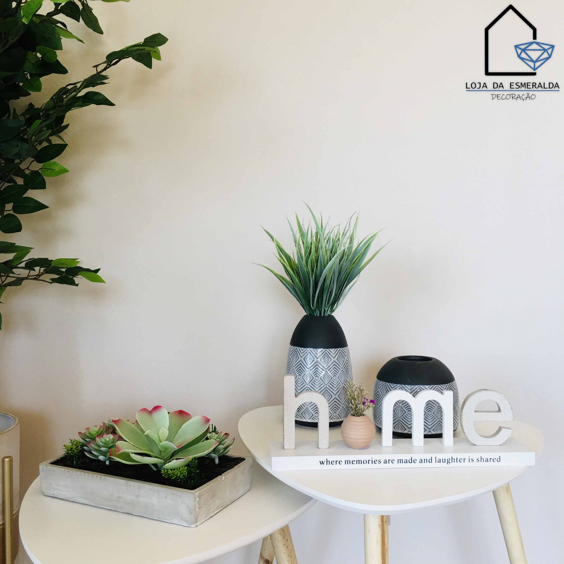 Decoração com palavra 'home', vasos cinzentos e plantas artificiais em mesas brancas