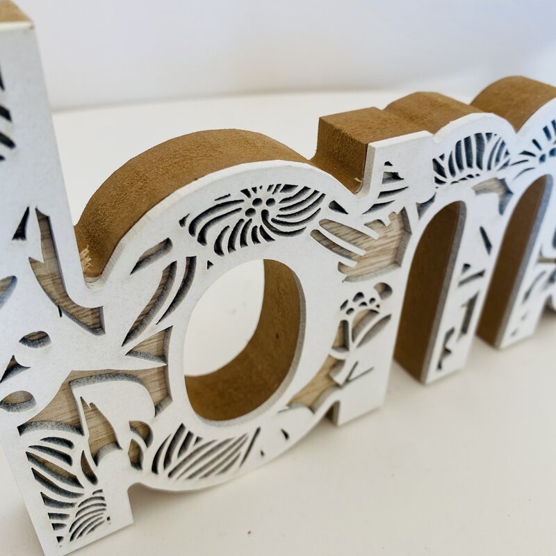 Objeto decorativo em madeira com palavras recortadas em padrão floral