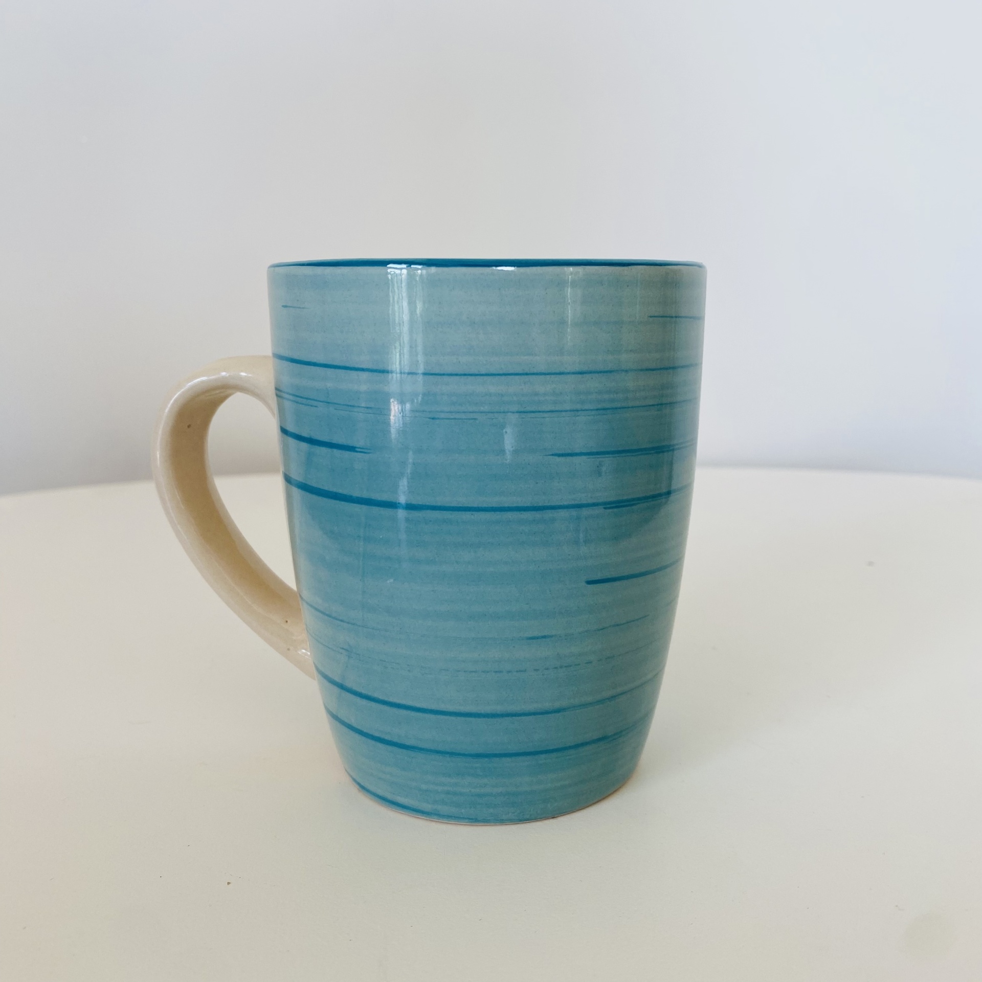 Caneca cerâmica azul com riscas horizontais e asa bege