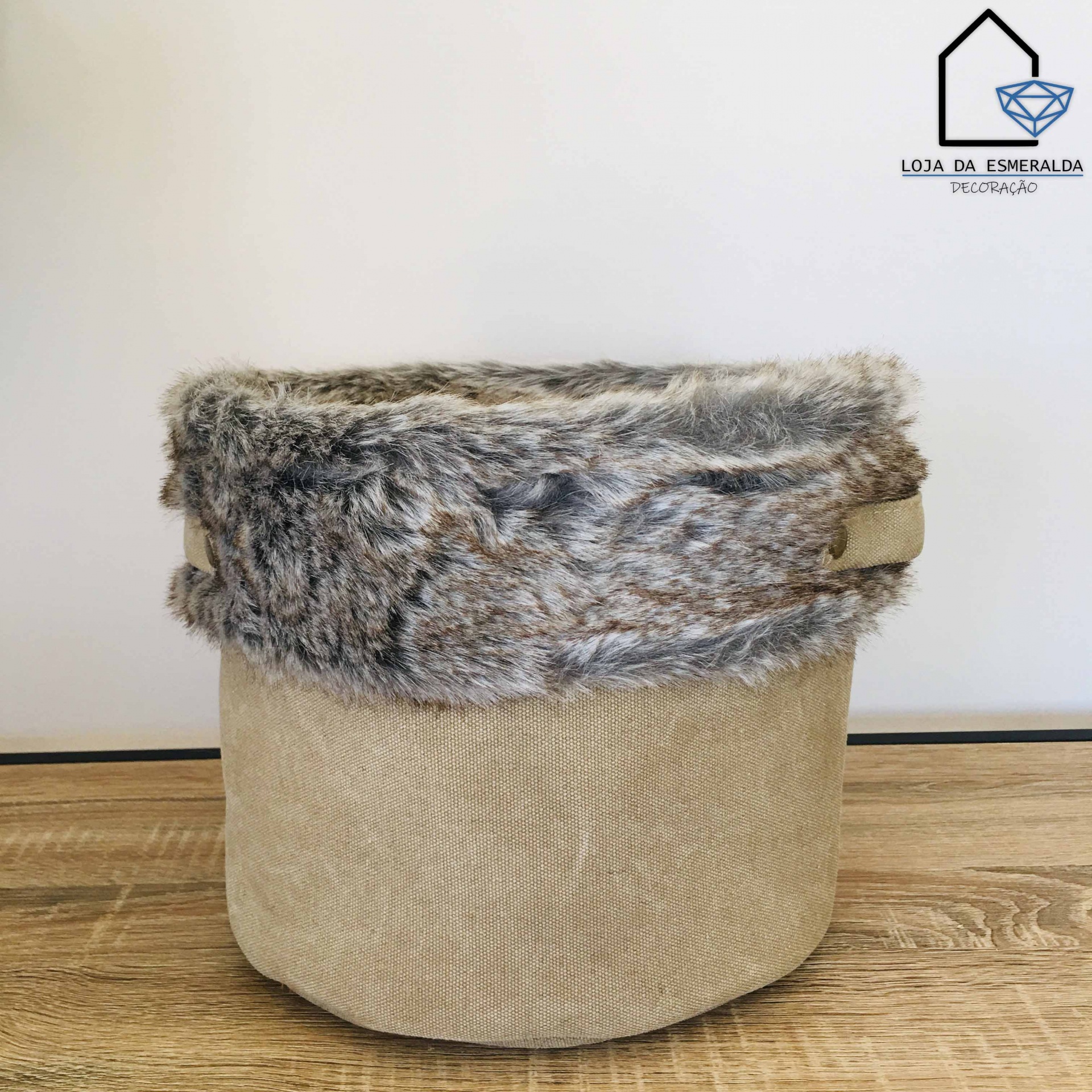 Cesto bege com aba de pelúcia cinzenta sobre superfície de madeira