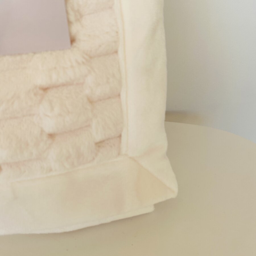 Cantinho de almofada felpuda bege claro sobre superfície clara