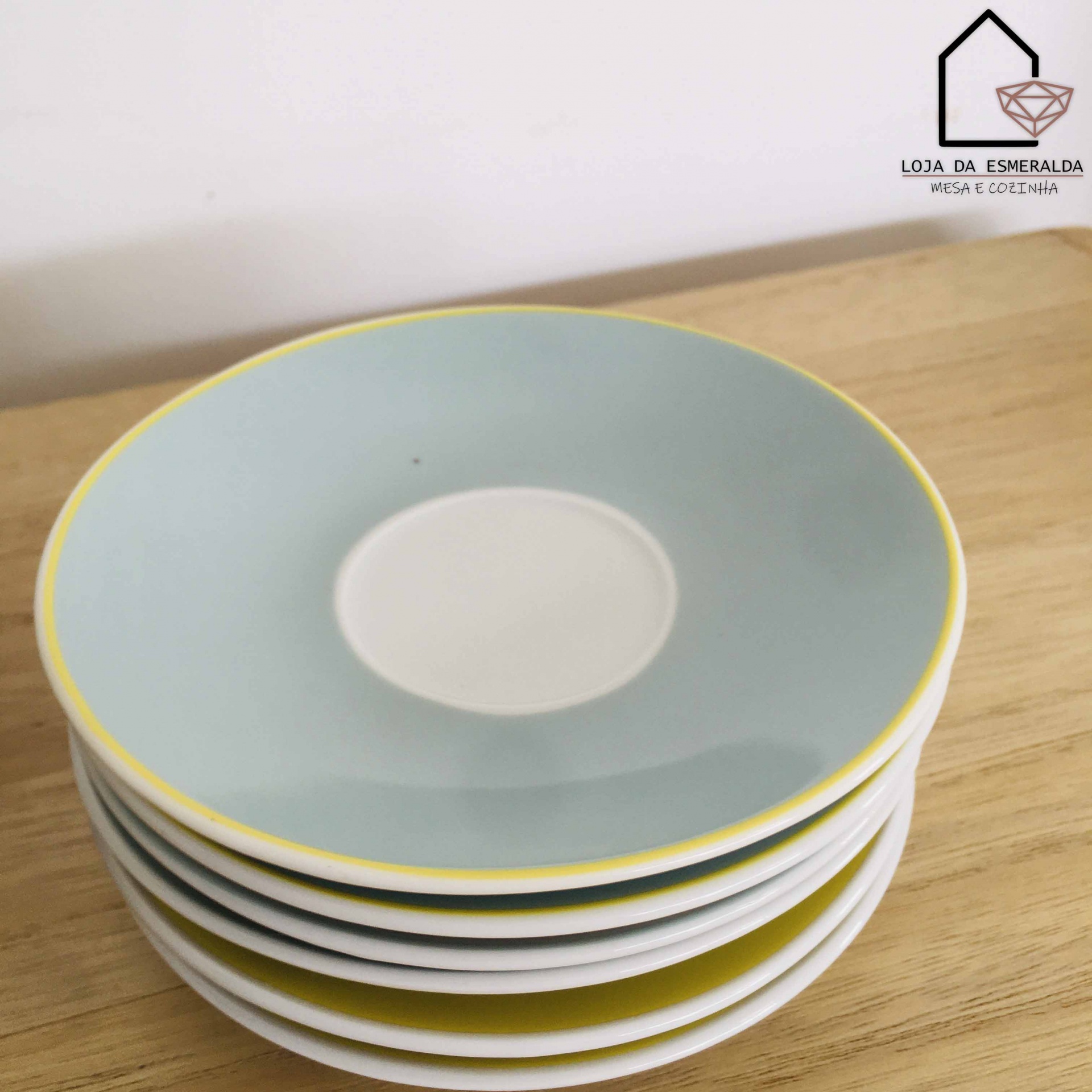 Conjunto de seis pratos cerâmicos azul claro e amarelo empilhados sobre madeira com logótipo Loja da Esmeralda