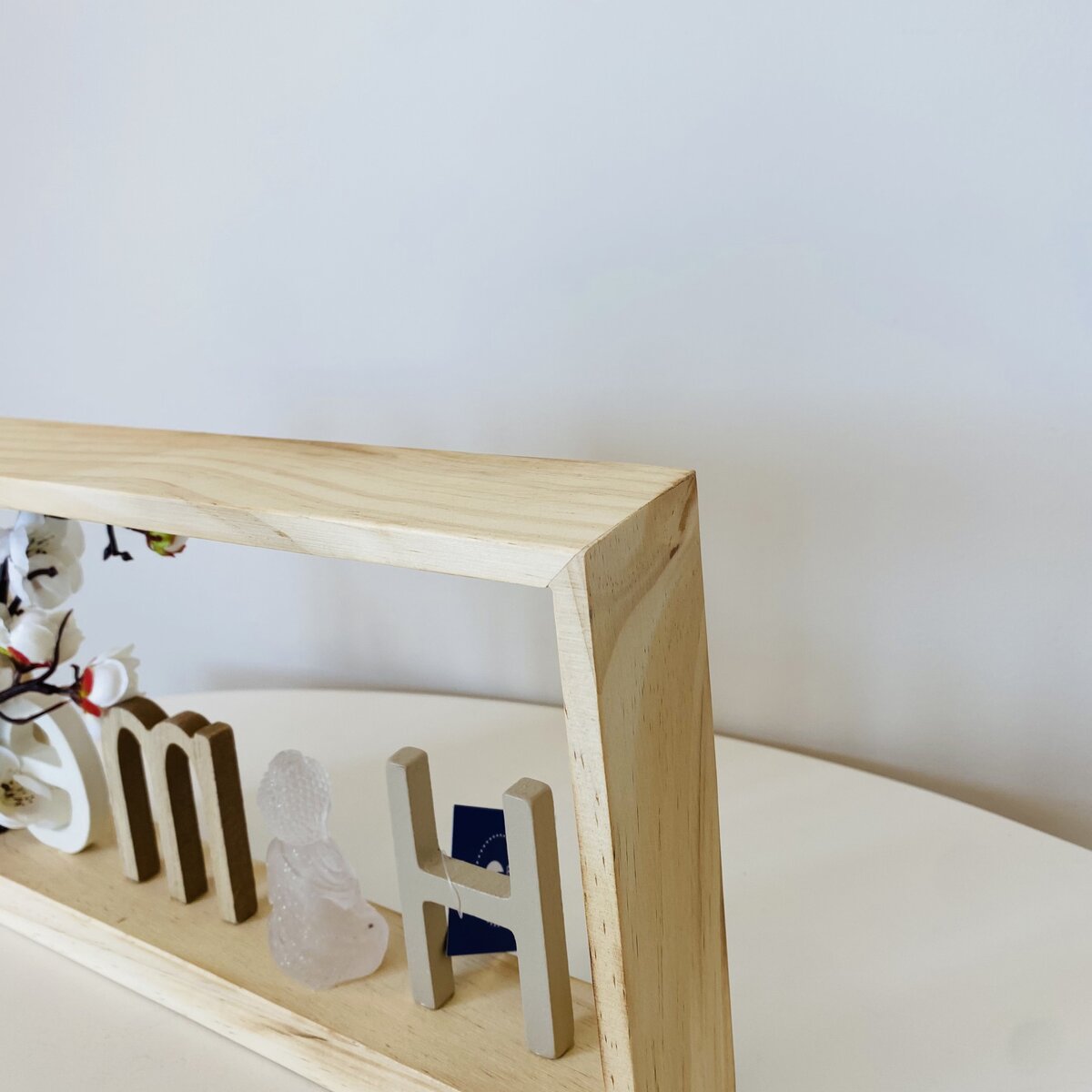 Estrutura decorativa de madeira clara com letras e figuras em resina