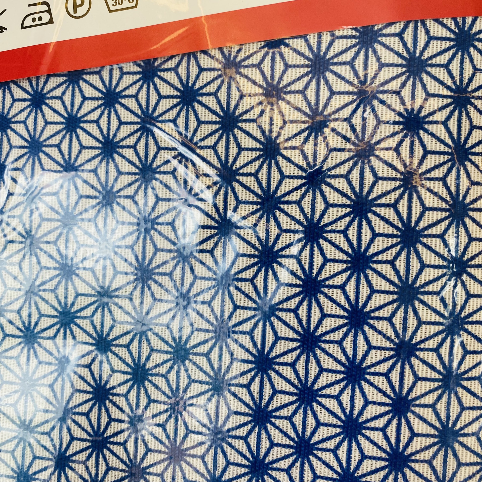 Tecido azul e branco com padrão geométrico e borda vermelha