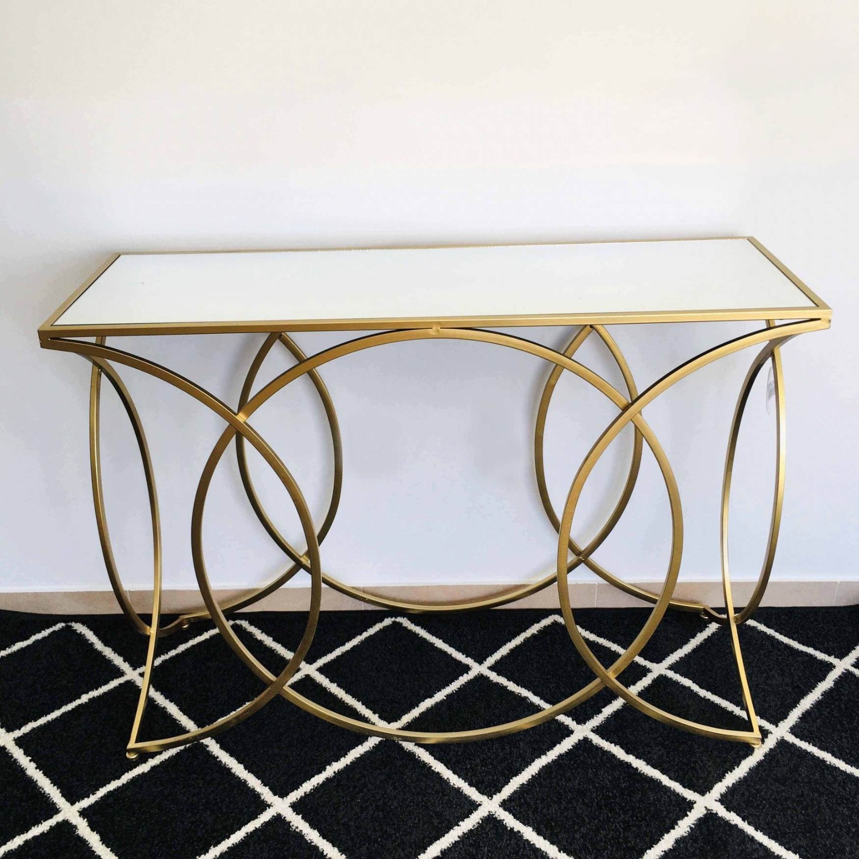 Aparador com tampo branco e estrutura metálica dourada com design circular