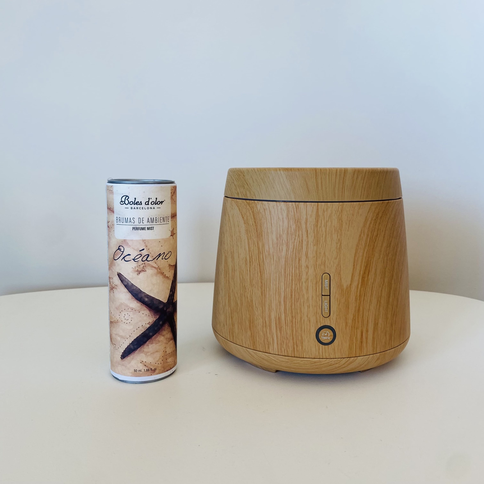 Difusor de aroma em madeira clara ao lado de frasco cilíndrico decorado com estrela-do-mar