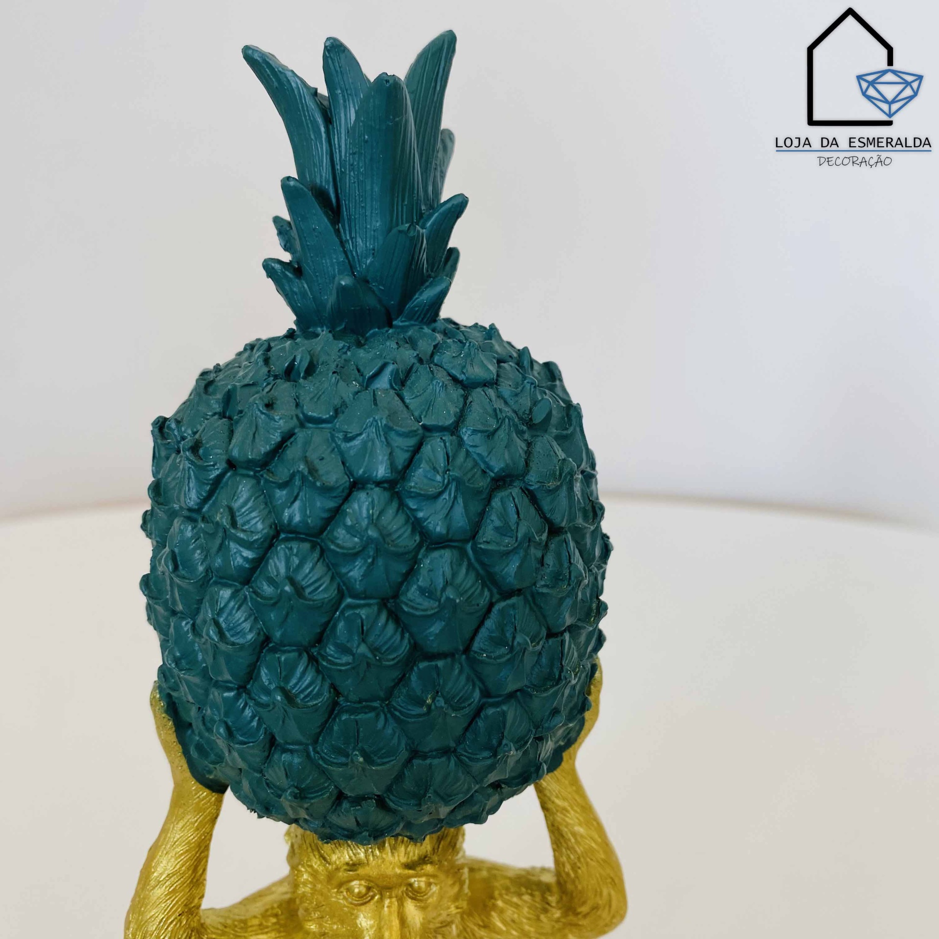 Estátua de abacaxi verde com base dourada em superfície branca
