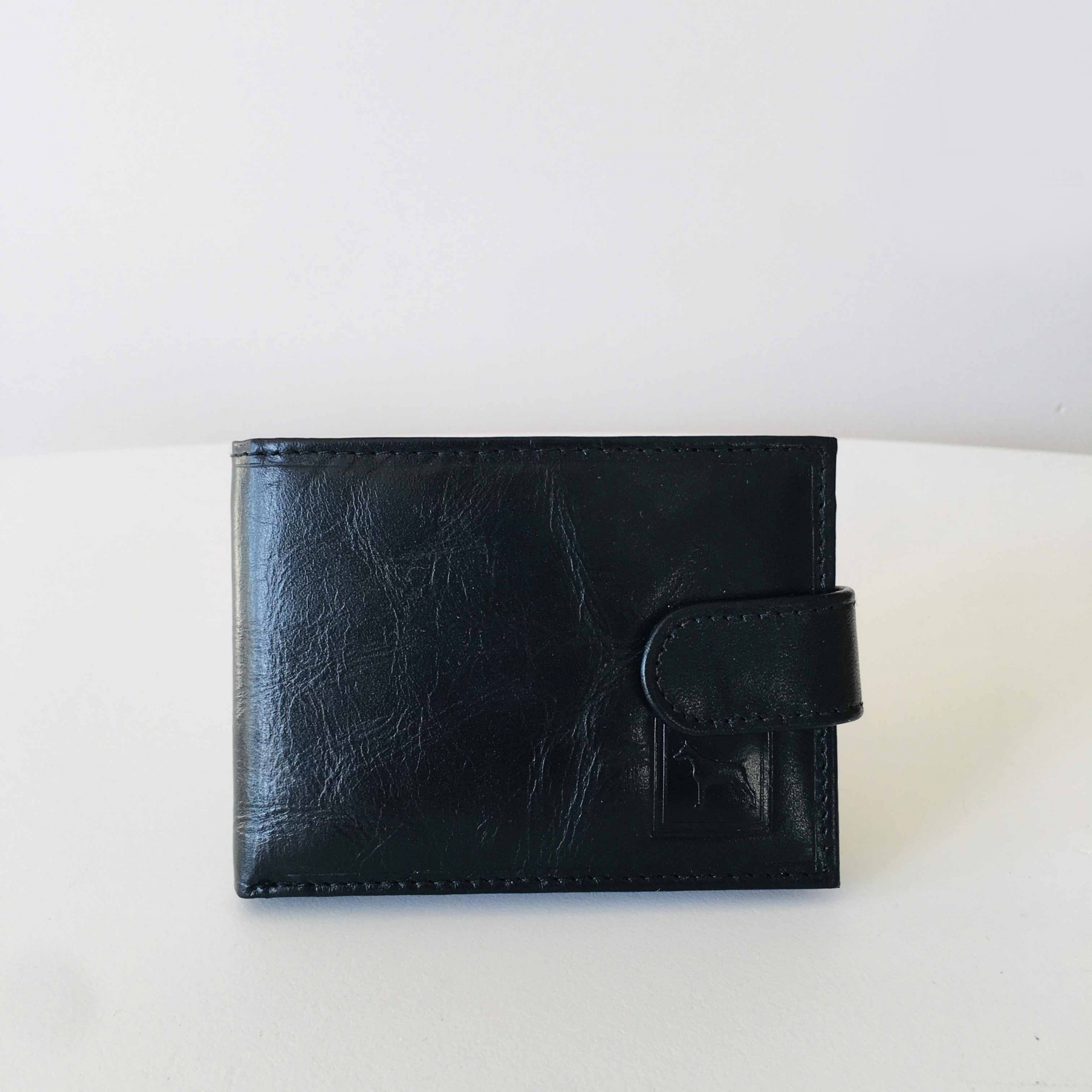 Carteira preta em pele sobre superfície branca