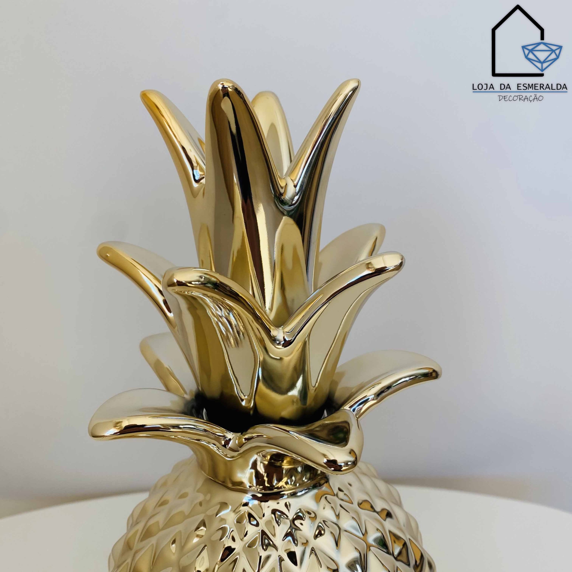 Estatueta dourada em forma de ananás decorativo com logotipo ao fundo