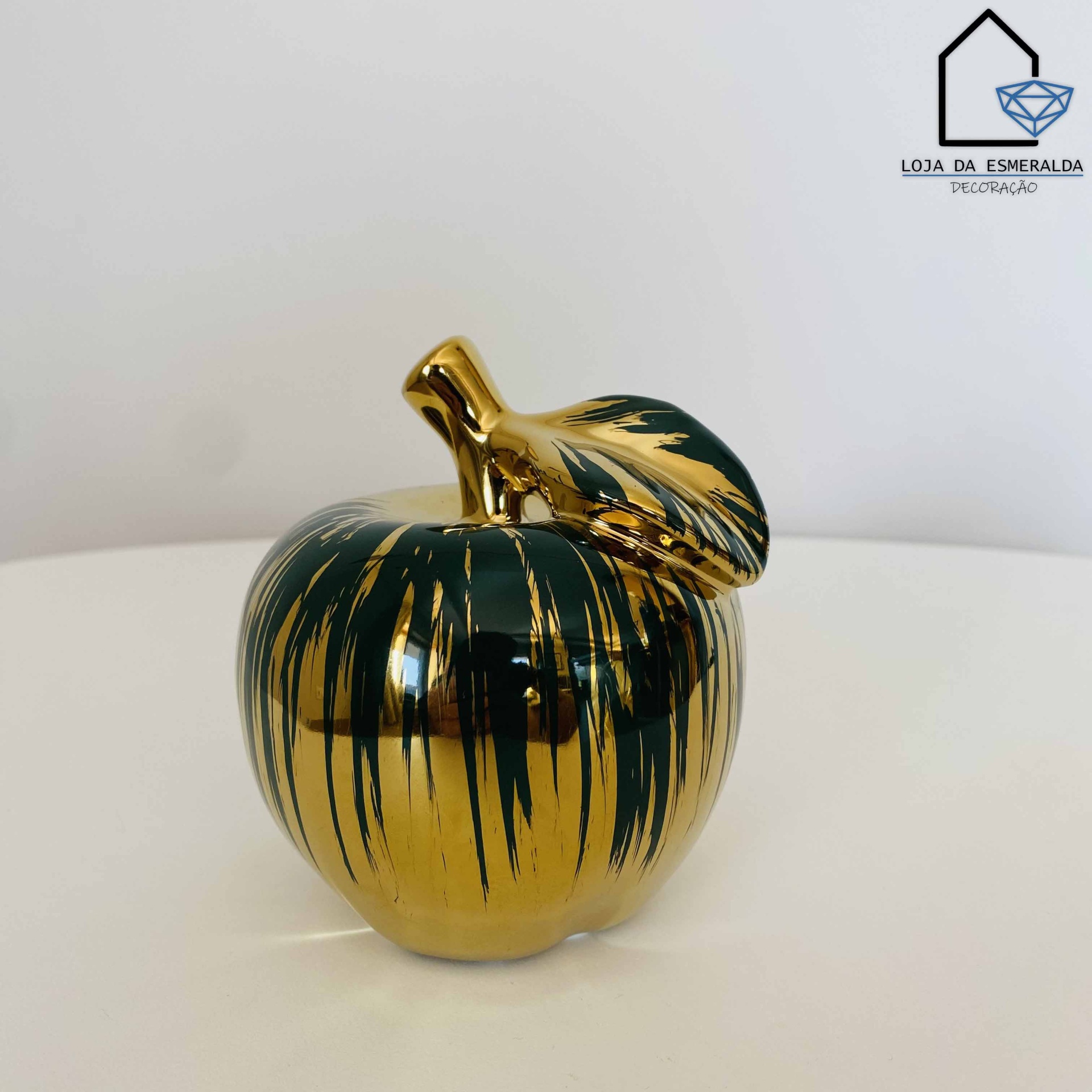 Maçã decorativa dourada com pinceladas pretas em fundo branco e cinza