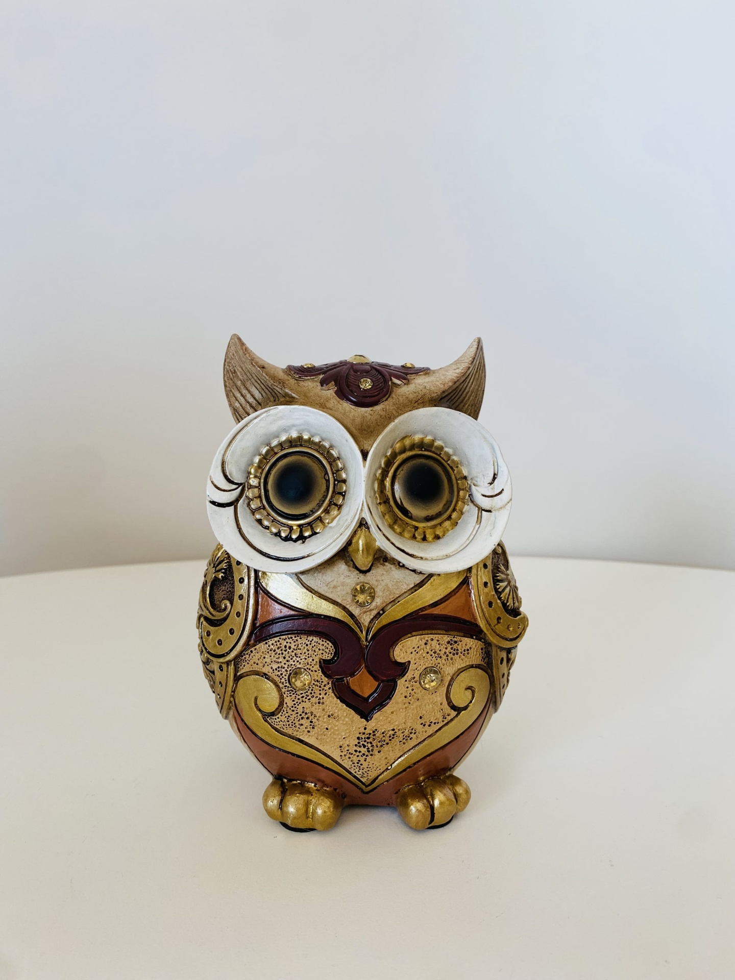 Estatueta de coruja decorativa em metal dourado e castanho com olhos grandes brancos