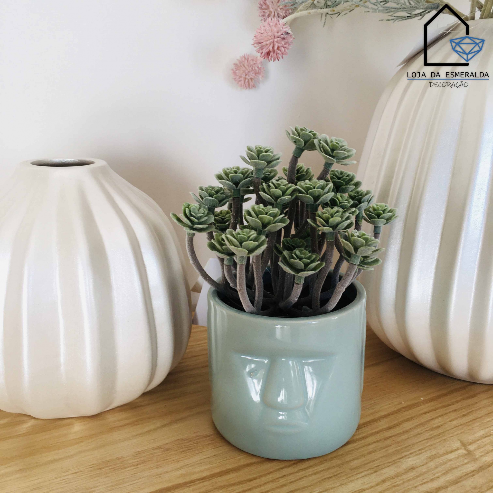 Vasos cerâmicos brancos canelados e vaso azul claro com planta suculenta artificial sobre madeira